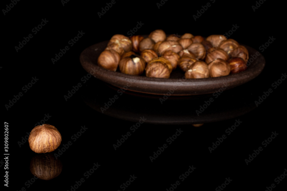 Lot of whole peeled tasty brown hazelnut with brown ceramic coaster isolated on black glass Lot of whole peeled tasty brown hazelnut with brown ceramic coaster isolated on black glass