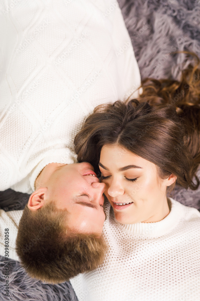Young beautiful couple lies on the floor in a beautiful white room and smiling Young beautiful couple lies on the floor in a beautiful white room and smiling