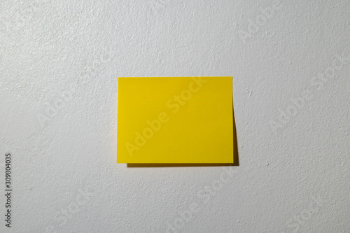 yellow post it note in the white cement wallpaper. 