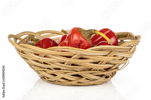 Lot of whole pickled red pepper in round rattan bowl isolated on white background