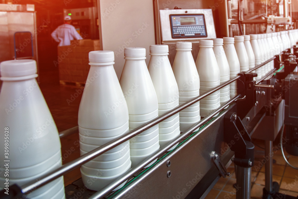 White plastic milk bottles on the conveyor on a modern dairy plant