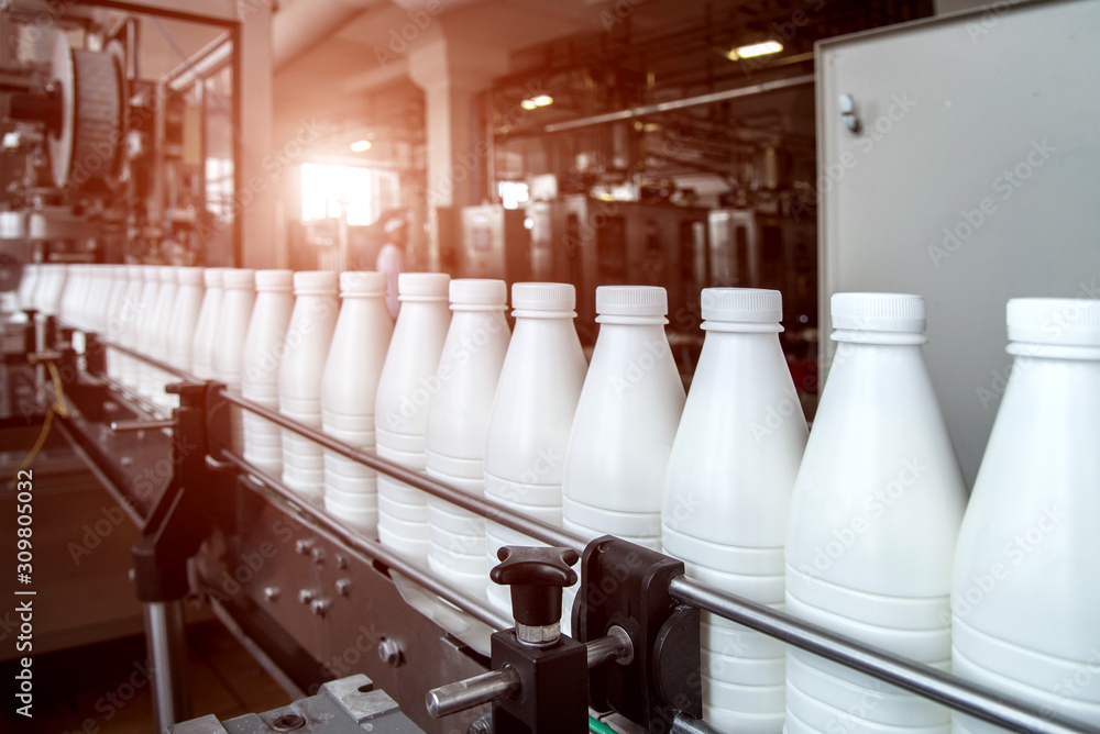 White plastic milk bottles on the conveyor on a modern dairy plant