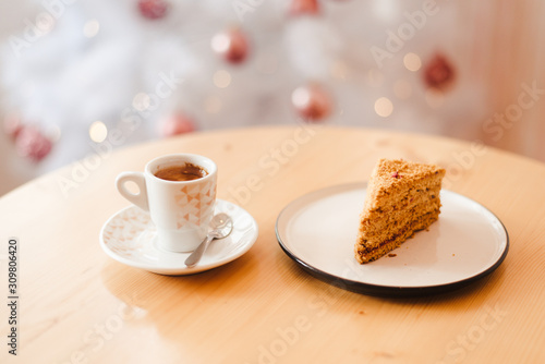 Italian coffee Cup and honey cake on the table near the Christmas tree with white bokeh