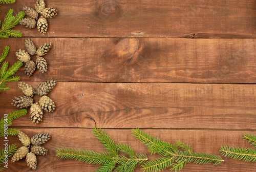 Green christmas tree branch and pine cones on wooden background