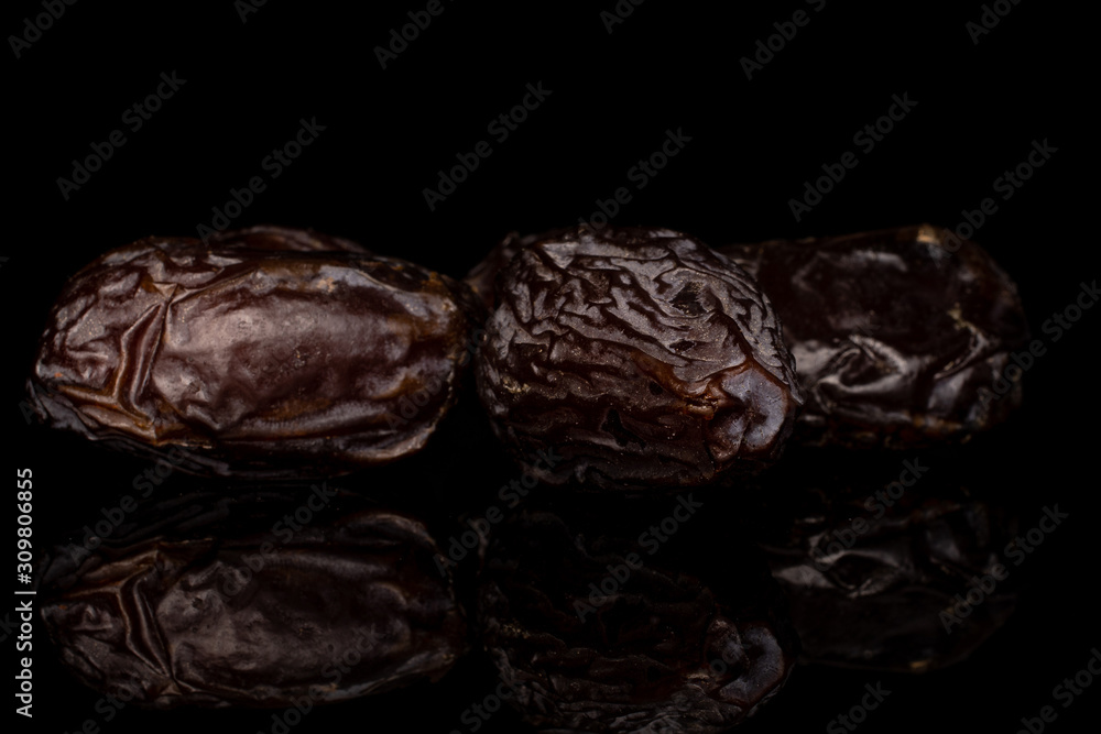 Group of three whole dried brown date fruit isolated on black glass Group of three whole dried brown date fruit isolated on black glass