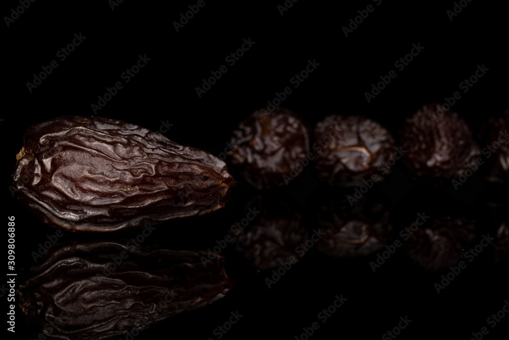 Group of four whole dried brown date fruit isolated on black glass Group of four whole dried brown date fruit isolated on black glass