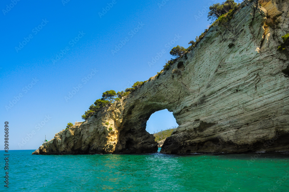 Naklejka premium Mediterranean sea coast landscape, blue clear sky and sea, with an opening in the rock.