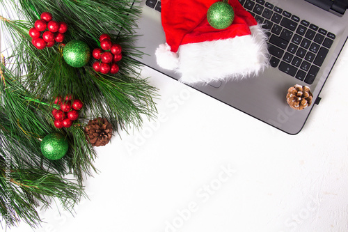 Office white table with computer, pine branch and santa hat. Christmas background. Copy space. © wings2016