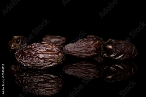 Group of five whole dried brown date fruit isolated on black glass