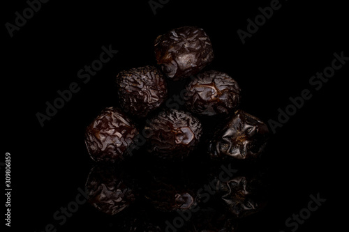 Group of six whole dried brown date fruit isolated on black glass