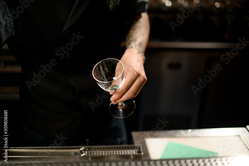 Bartender holding cocktail glass above bar counter