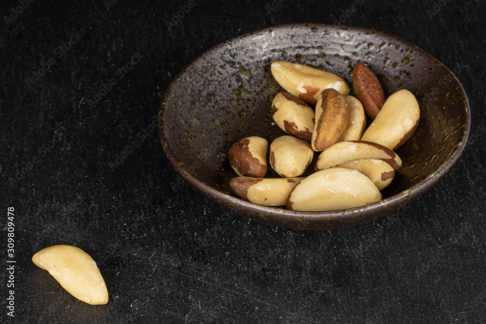 Lot of whole brazil brown nut in glazed bowl on grey stone Lot of whole brazil brown nut in glazed bowl on grey stone