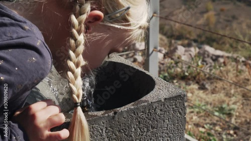 Two little blonde caucasian sisters drinking from fountain photo