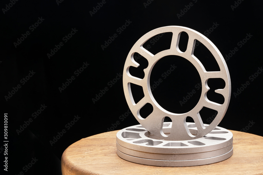Obraz premium Automotive parts - close up new stainless metal remote adapter spacer wheel hub of the car on black background