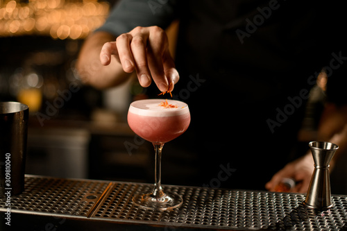 Close up of bartender decorating alcohol cocktail