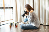 Portrait of young beautiful Asian girl use DSLR camera to take photo of cactus on the floor in living room at her home. Blogger and freelance working online marketing. Startup Small Business owner.