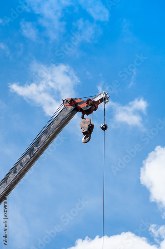 Mobile crane boom with hook hanging by wire cable background blue sky,close up