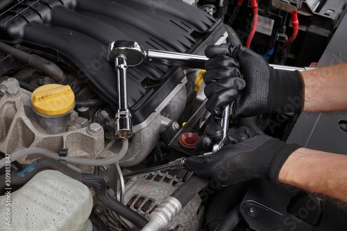 Car repair shop. Tightening the car element with a ratchet wrench.