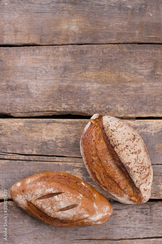 Artisan bread on wooden background, top view. Two loaves of freshly baked bread on kitchen table. Space for text.