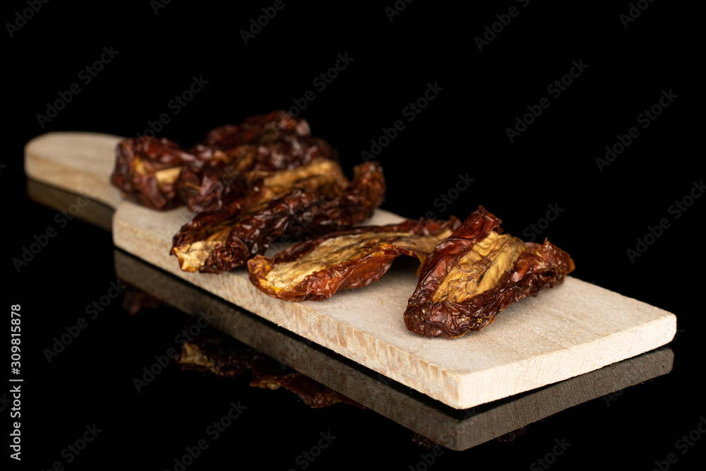 Group of five whole dried red tomato piece on wooden cutting board isolated on black glass Group of five whole dried red tomato piece on wooden cutting board isolated on black glass