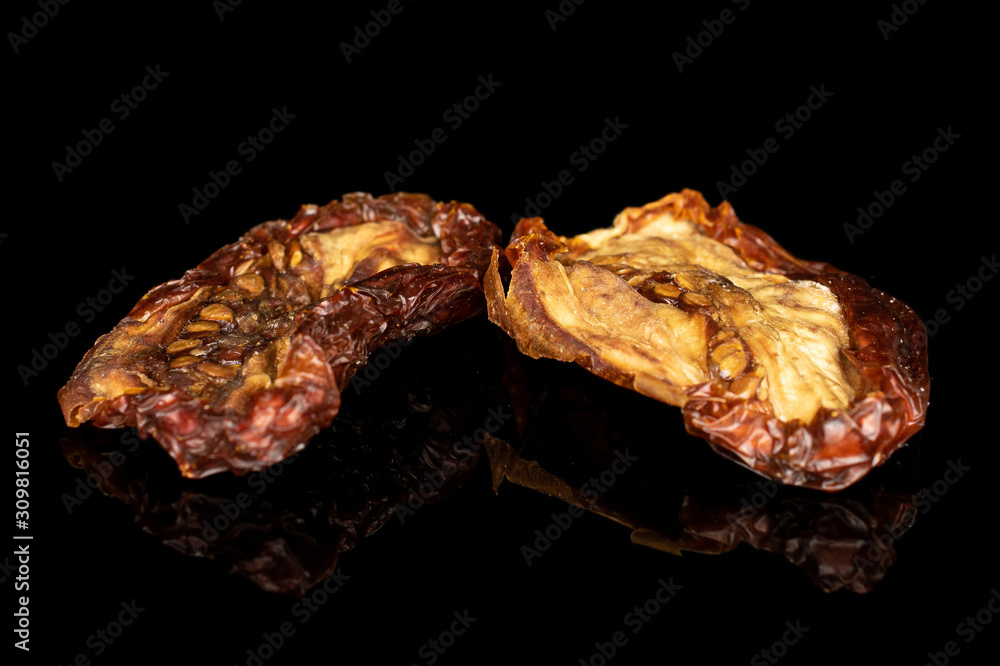 Group of two whole dried red tomato piece isolated on black glass Group of two whole dried red tomato piece isolated on black glass
