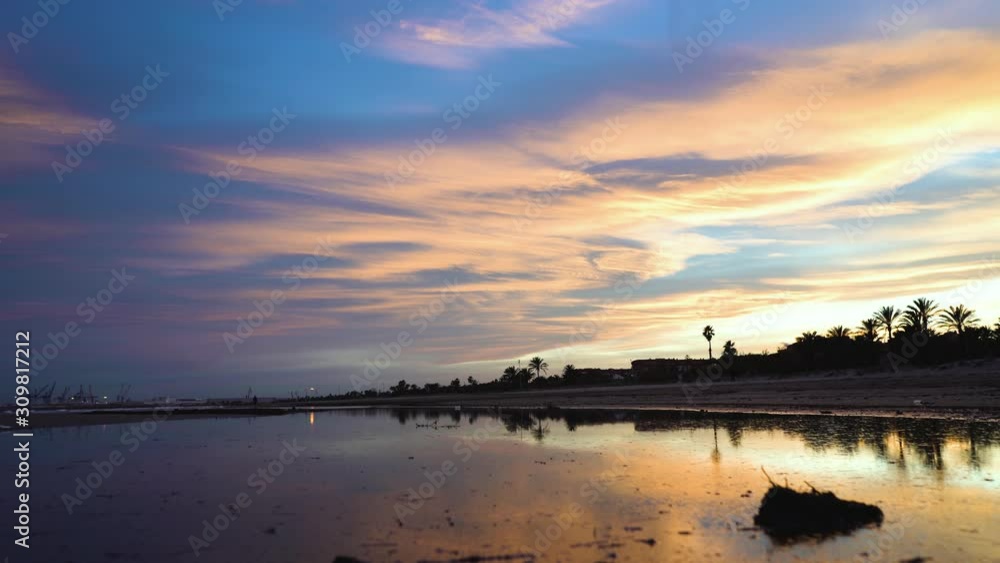 Beautiful sequence of beach with amazing sunset blue and golden sunset, a man walks away on the horizon, beyond the lake where the sky is reflected with clouds and colors Beautiful sequence of beach with amazing sunset blue and golden sunset, a man walks away on the horizon, beyond the lake where the sky is reflected with clouds and colors