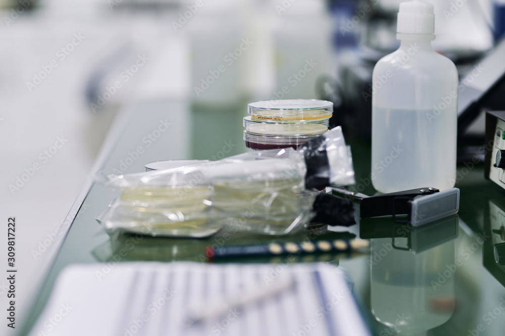 Petri dishes, distilled water and some other tools on a laboratory table. Shallow depth of field