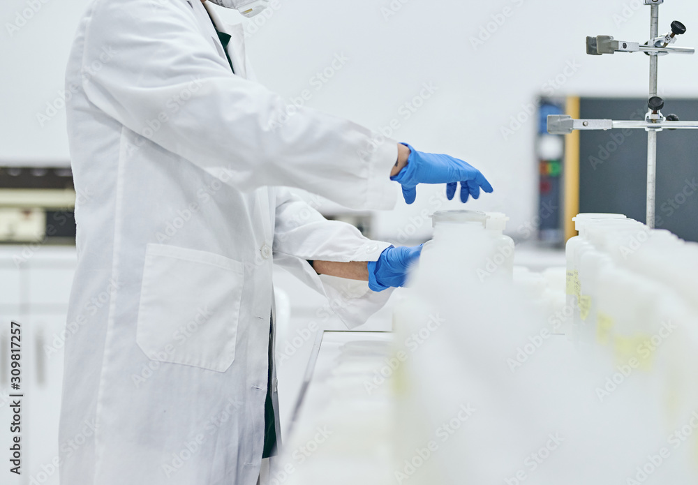 Women's hands in white coats and blue lab gloves opening sample bottles. Woman scientist working in the lab. Shallow depth of field Women's hands in white coats and blue lab gloves opening sample bottles. Woman scientist working in the lab. Shallow depth of field
