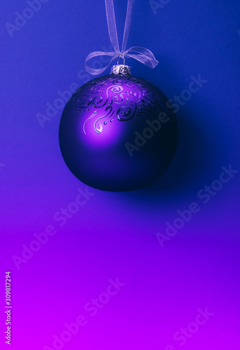 Neon colored gradient Christmas ball hanging on a ribbon. Copy space.