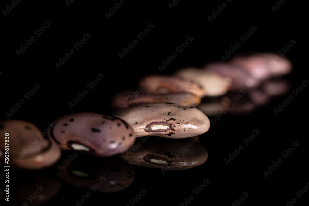 Lot of whole dried fresh speckled bean pinto isolated on black glass Lot of whole dried fresh speckled bean pinto isolated on black glass