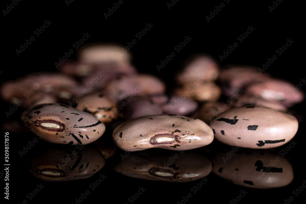 Lot of whole fresh speckled bean pinto isolated on black glass Lot of whole fresh speckled bean pinto isolated on black glass