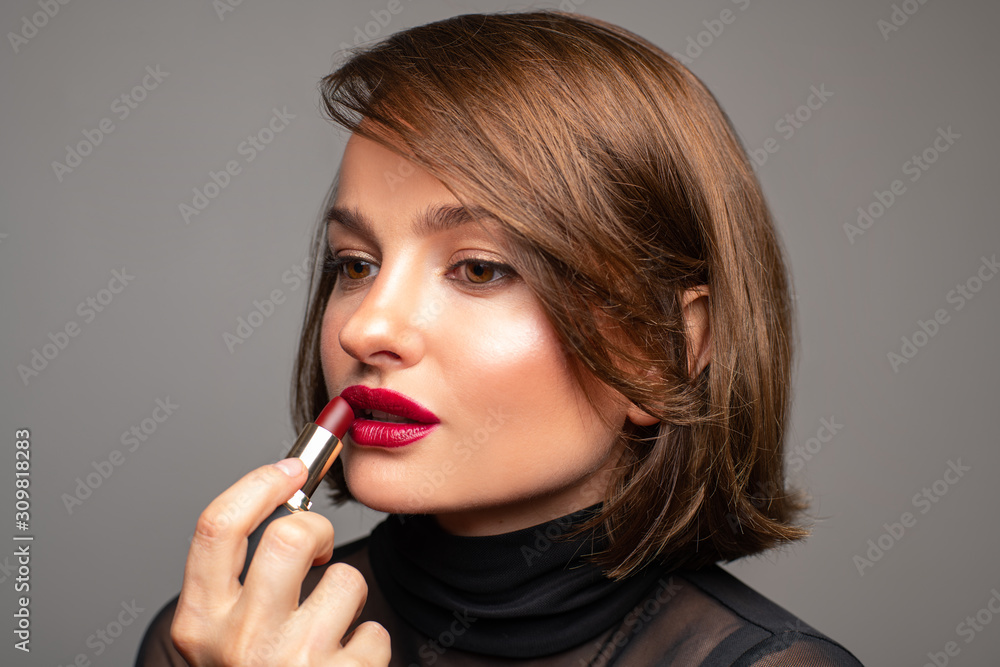 Professional Makeup. Beautiful brunette woman is applying red lipstick. Professional Makeup. Beautiful brunette woman is applying red lipstick.