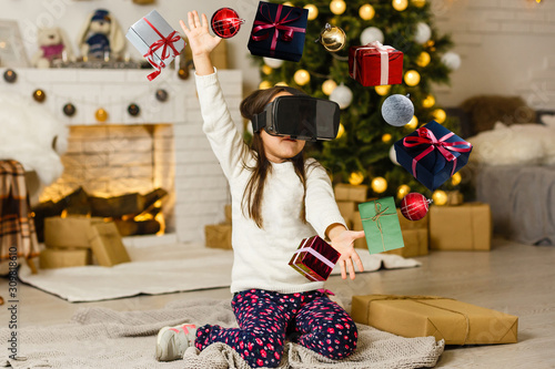 Fotografie Portrait of little girl playing in virtual reality headset at home