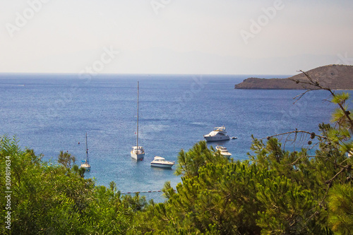 Beautiful panoramic view on Bodrum marina.Turkish vacation on the shores of Aegean sea. Stylish white buildings, green trees on foreground and yachts, boats on background. Bodrum city, Mugla, Turkey
