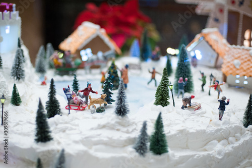 Little toy Christmas miniature with people skating and playing snowballs