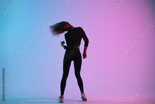 Fototapeta Naklejka Na Ścianę i Meble -  Charismatic young creative dancer posing in studio against colorful background. Sporty woman dance and her hair follow her head