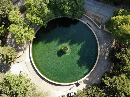 round fountain with green water in forest veiw from top down