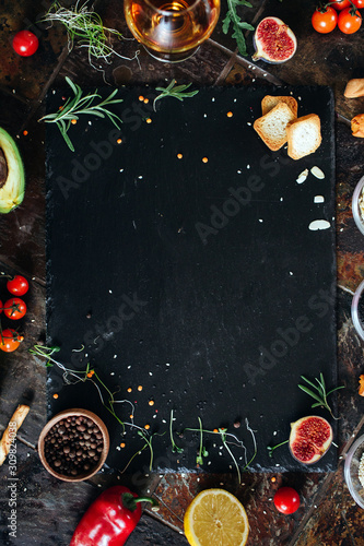 Cooking dark stone board with herbs, spices and vegetables. Top view with copy space