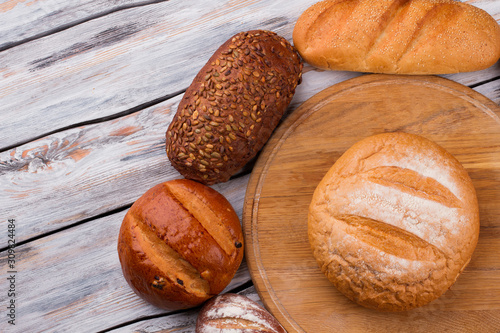 Various bread types on wooden background. Fresh artisan bread on cutting board. Food concept.