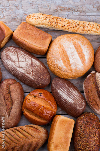 Variety of organic bread on wooden background. Top view of different types of bread. Organic farmers food market.
