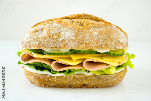 Food photography of a cold cut sandwich with ham, cheese and cucumbers on a white background
