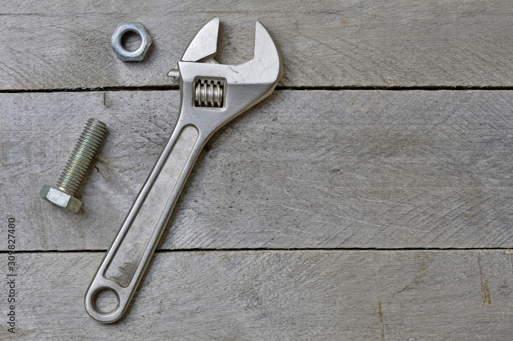 adjustable wrench and bolt on a wooden background. copy space. adjustable wrench and bolt on a wooden background. copy space.