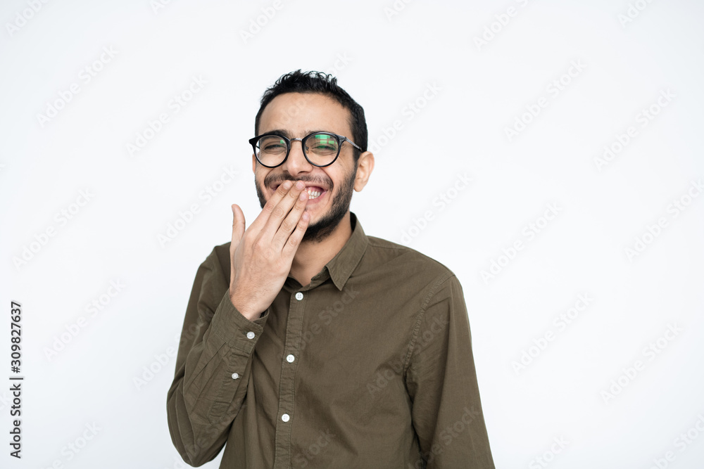 Young cheerful businessman in eyeglasses covering his mouth while laughing Young cheerful businessman in eyeglasses covering his mouth while laughing