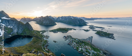 Panorama stitch of three pictures overlooking the city of Reine and Hamnoy in Lofoten, Norway. From top of the beautiful Reinebringen during the midnight sun. Ocean and mountain view. 