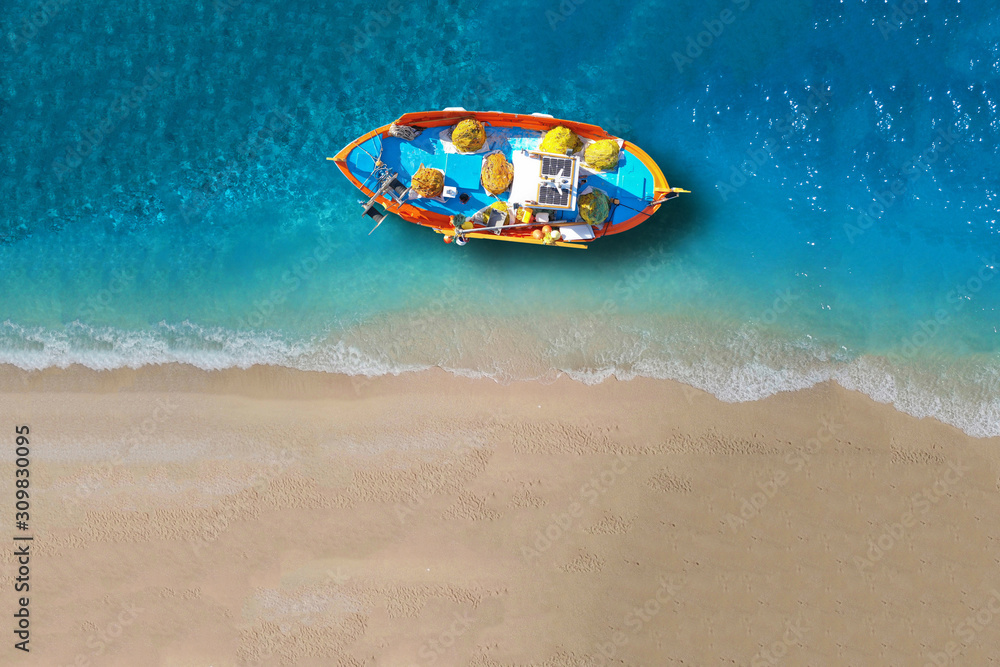 Obraz premium Aerial drone top down ultra wide photo of traditional picturesque wooden fishing boat in Crete island beach with turquoise sea, Greece