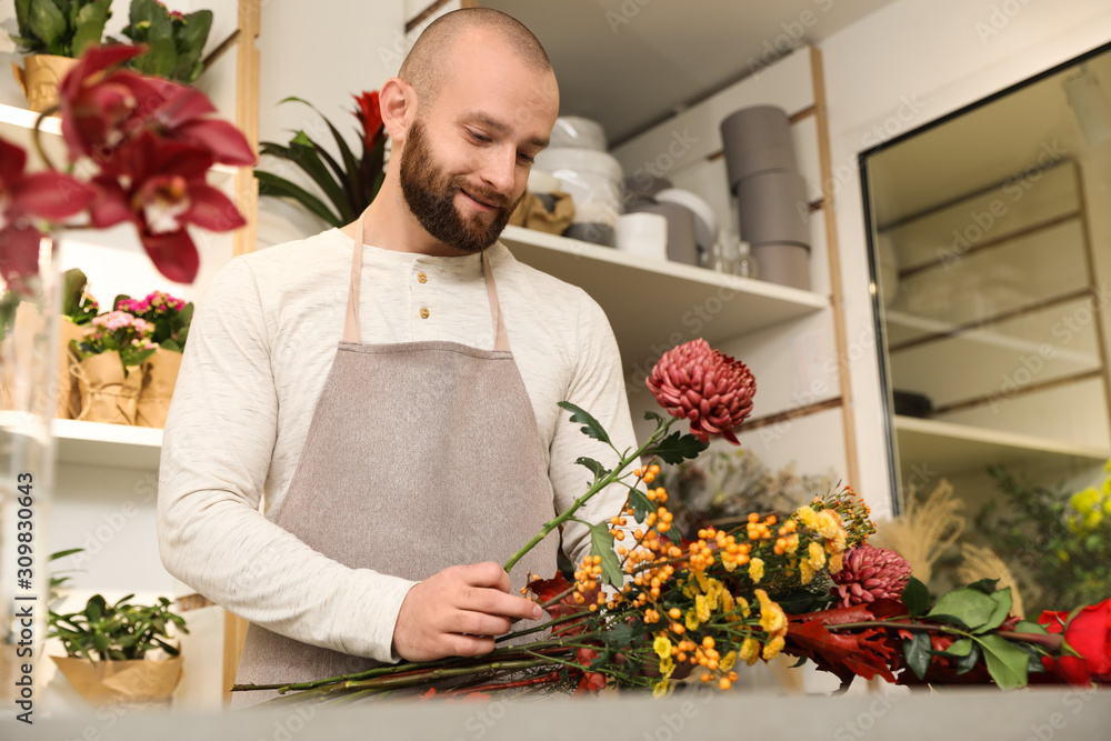 Florist making bouquet with fresh flowers at table in shop Florist making bouquet with fresh flowers at table in shop