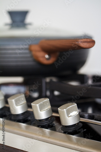 Close-up of a pan with a wooden handle on a gas stove, selective focus