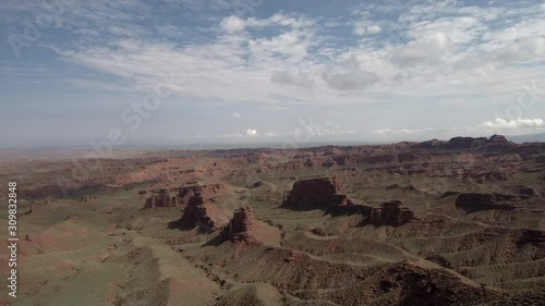 Flying over the Chinese Grand Canyon also known as Pingshan Grand Canyon in Gansu province, China. Beautiful steep brown hills, and sky slightly covered by clouds in the background.