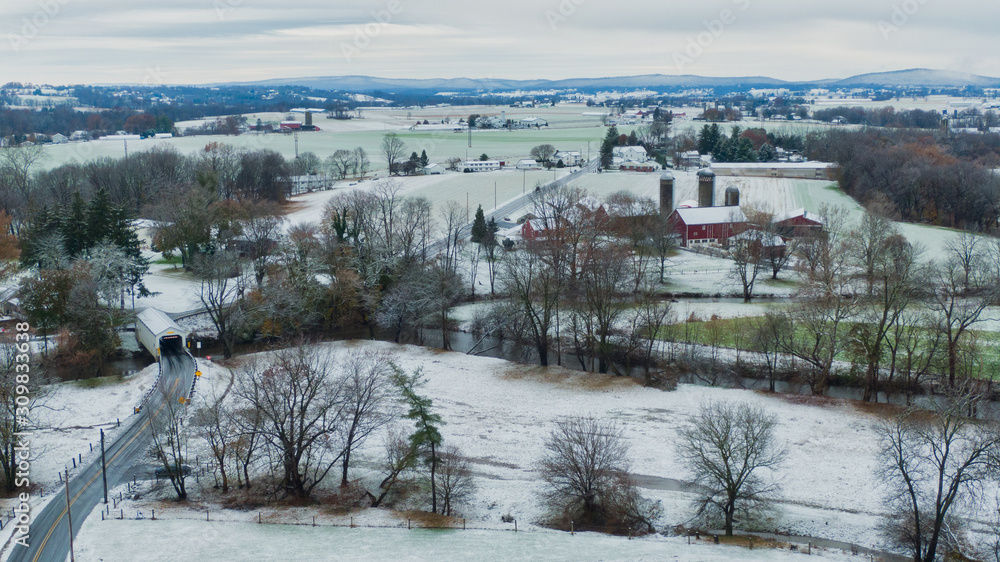 Pennsylvania aerial landscape in first snow, traditional farm and covered bridge, Keller's Mill in Lancaster County, PA