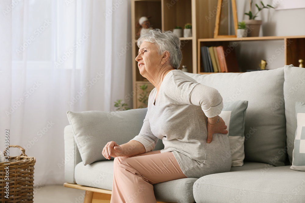Senior woman suffering from back pain at home Senior woman suffering from back pain at home